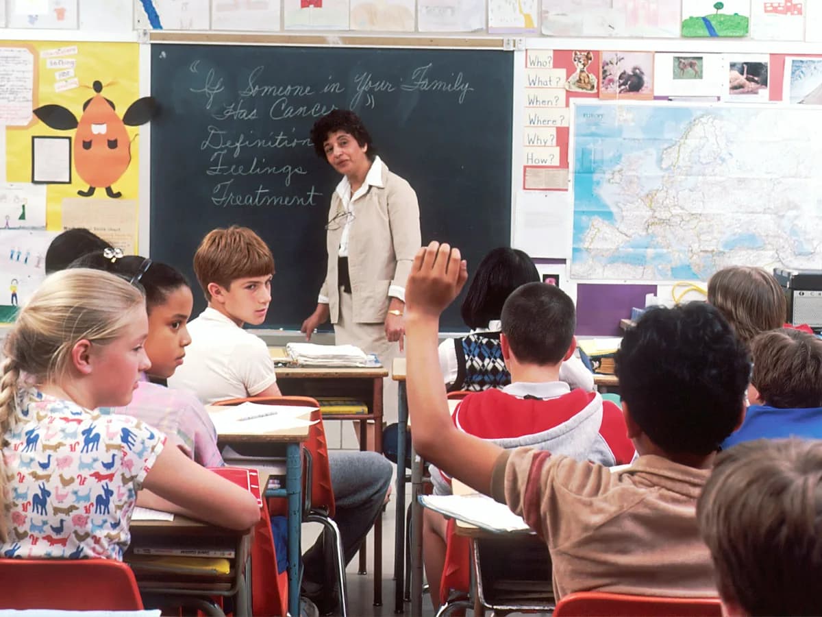 Des enfants en classe lèvent la main pendant un cours